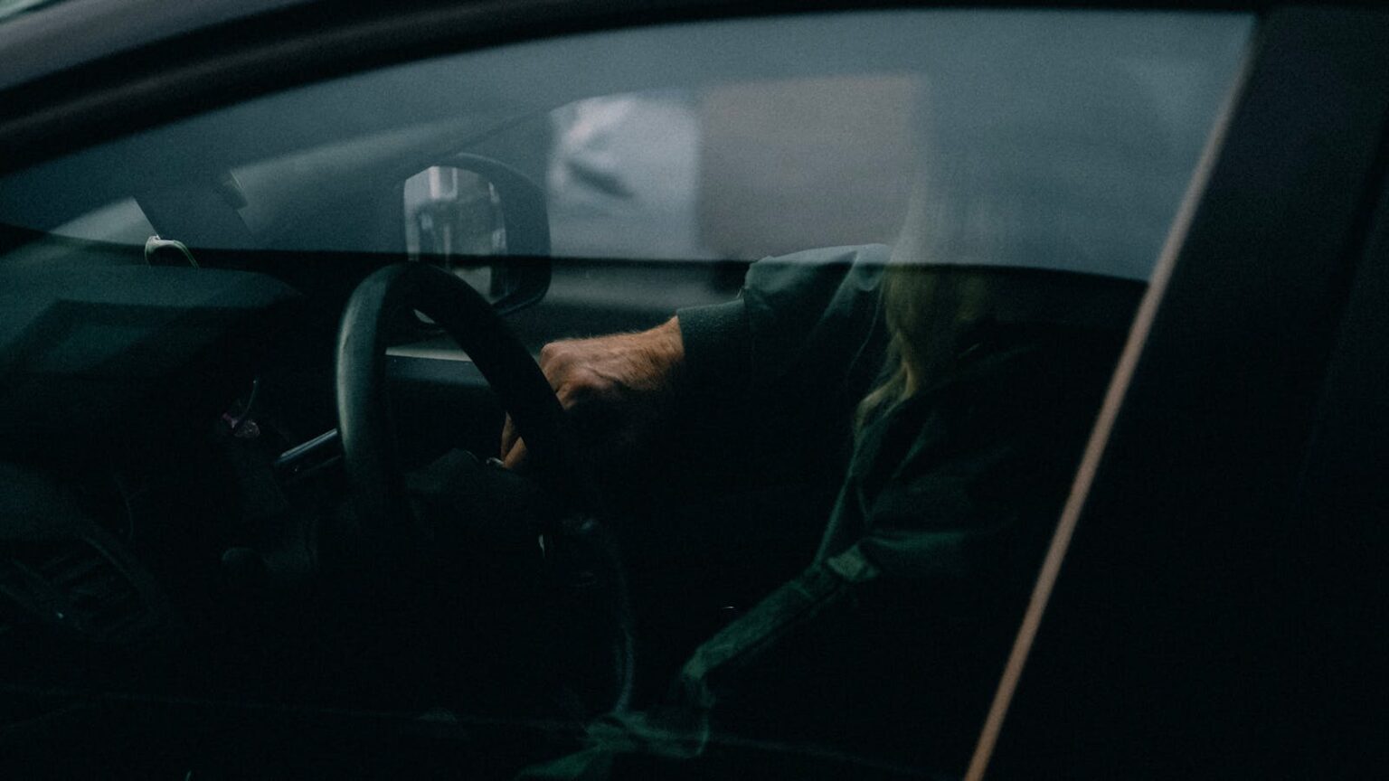 A person sitting inside a car with moody lighting